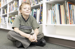 Little boy sitting in aisle of library 1
